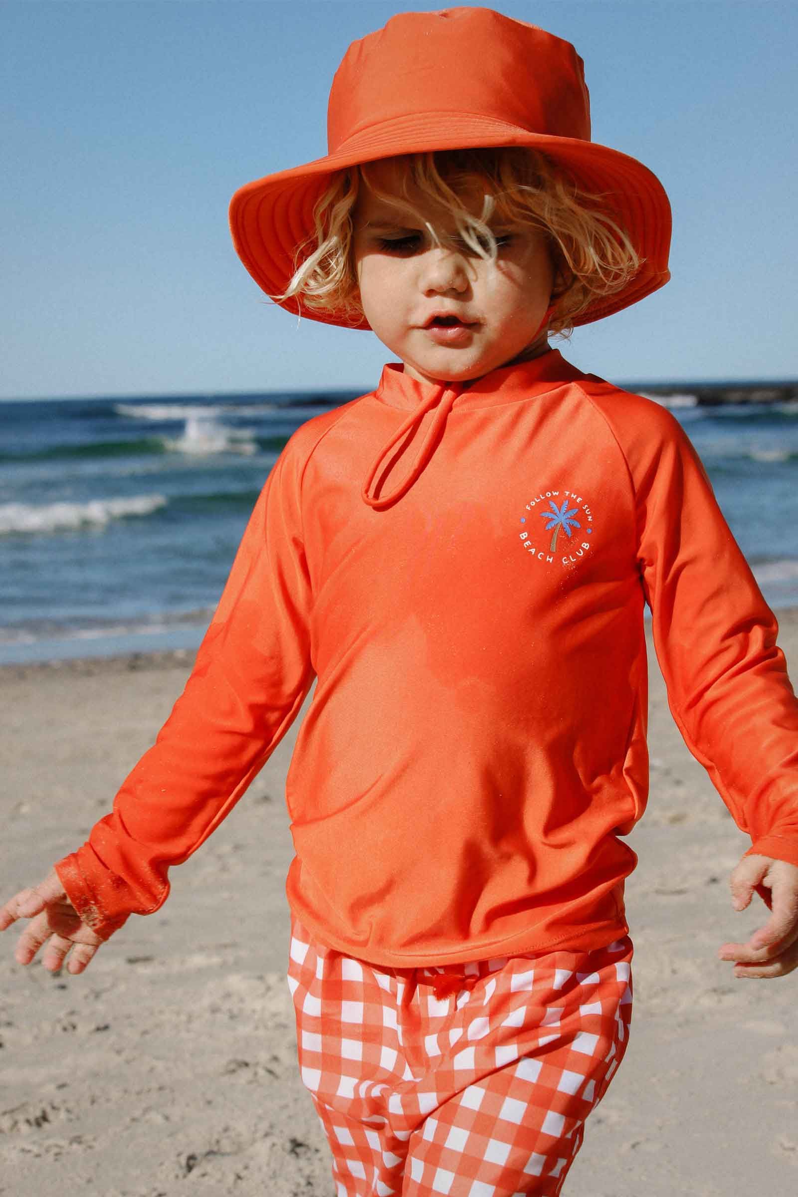 Child at the beach in Purebaby's Fiesta Gingham long sleeve rashie set