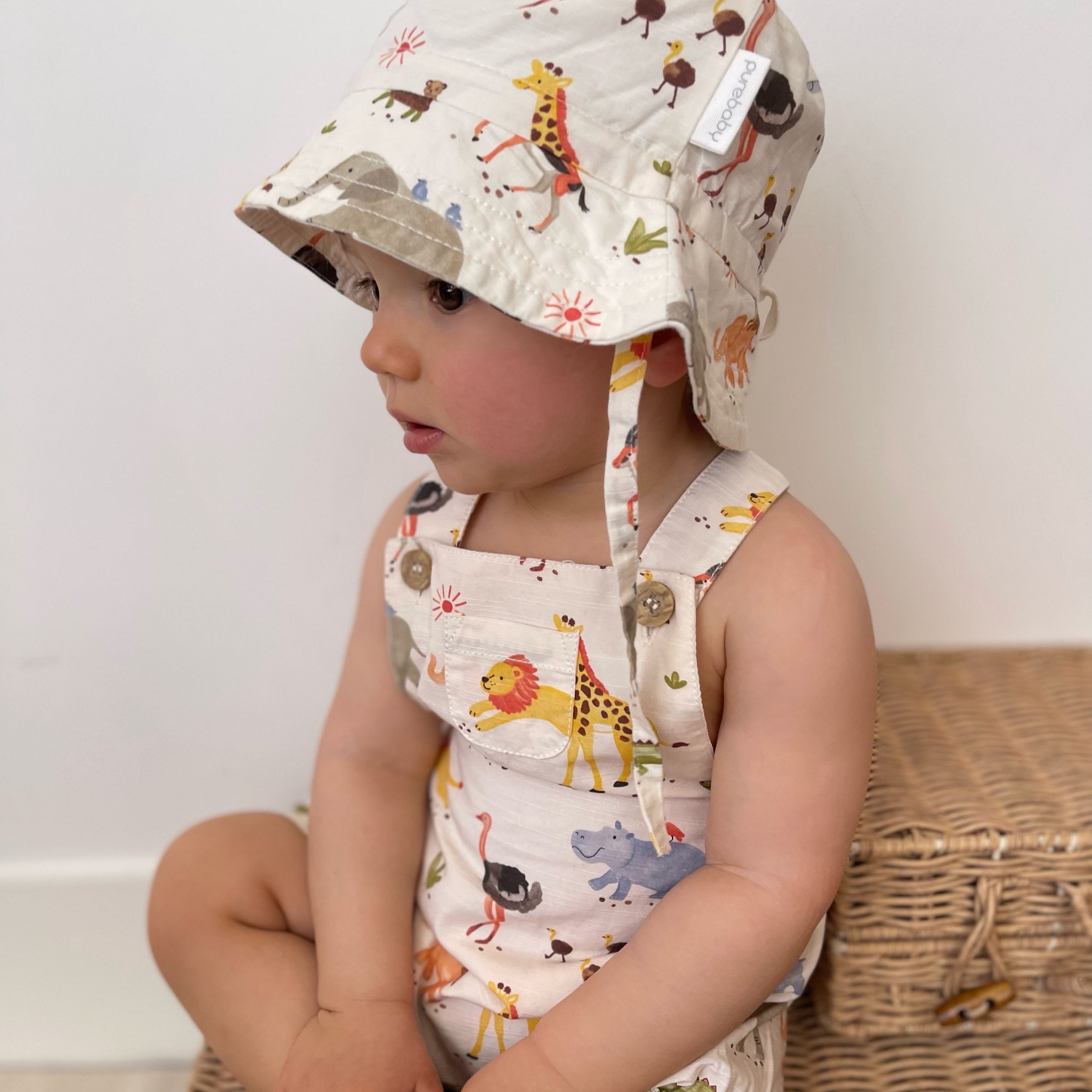 Baby wearing overalls and matching sun hat